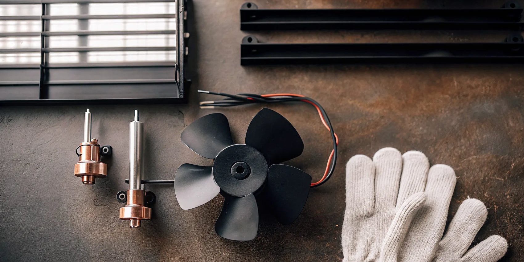 A wood stove fan replacement motor and new fan blade ready for installation.