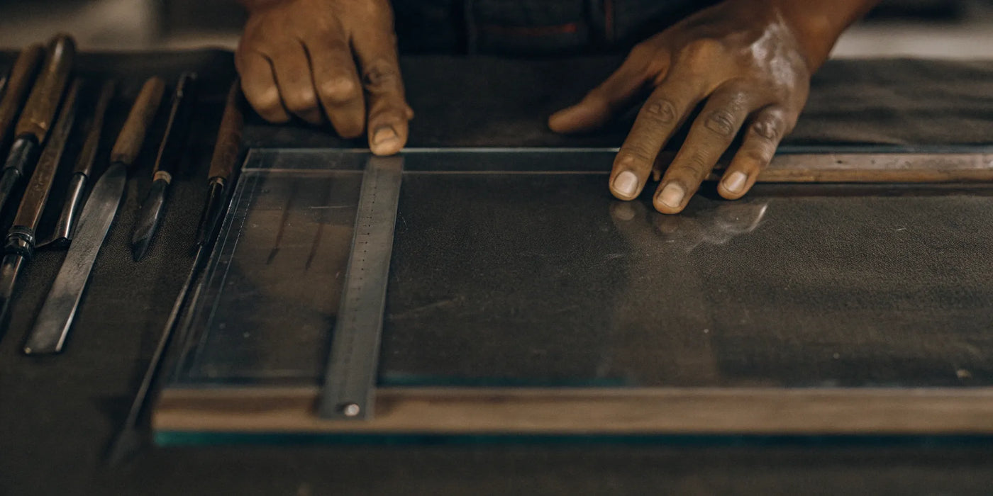A person measures a sheet of ceramic glass with a ruler to be cut to size.