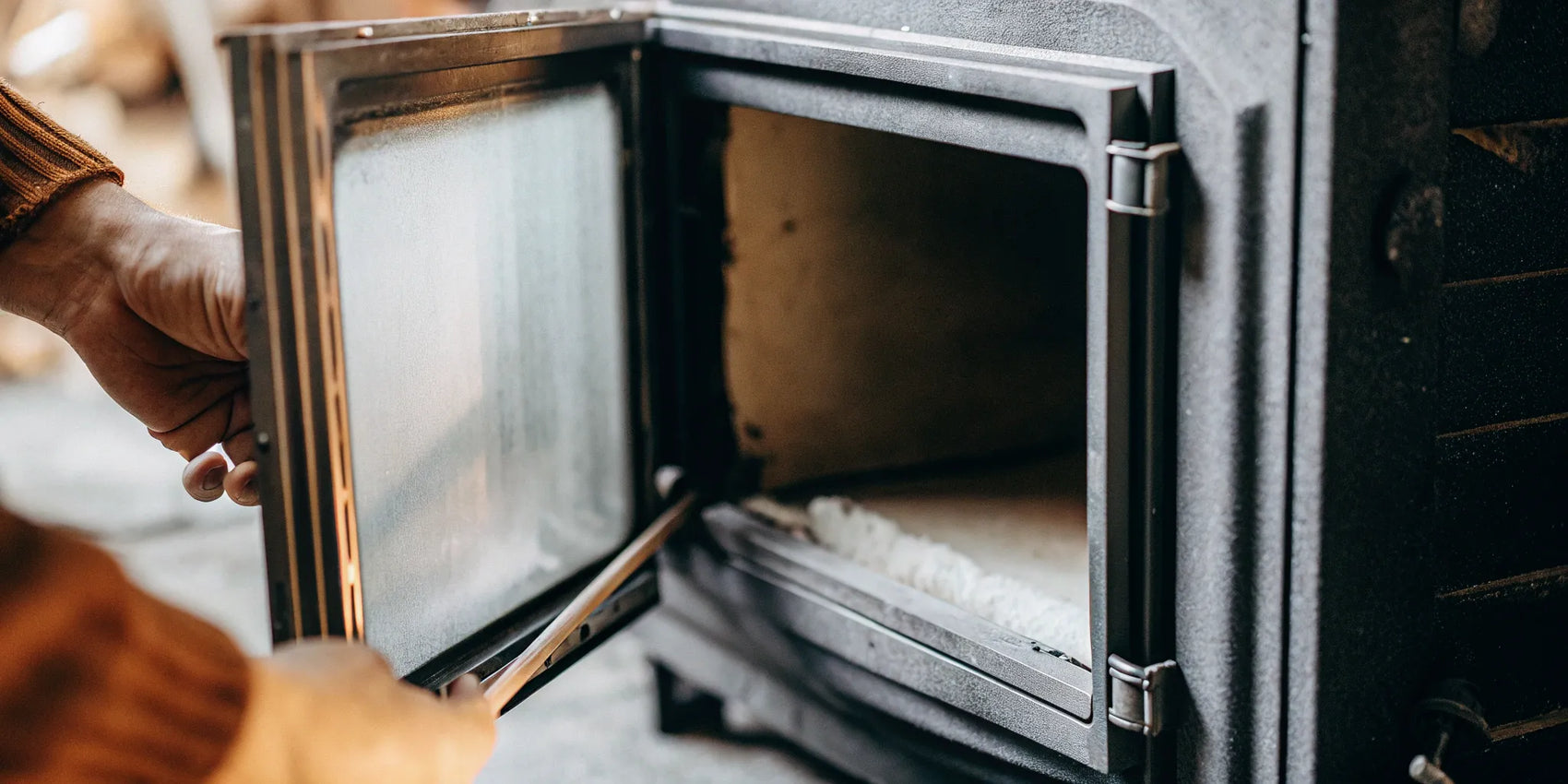 Opening a wood stove door to access the 1 inch gasket for replacement.