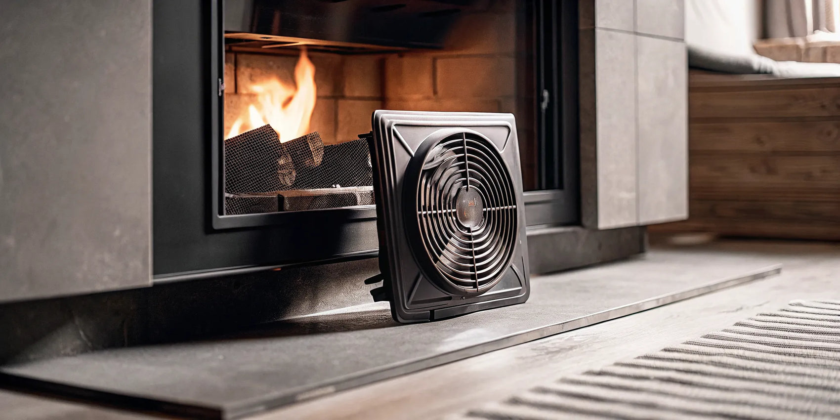 A fireplace blower kit with its components ready to install at the base of a fireplace.