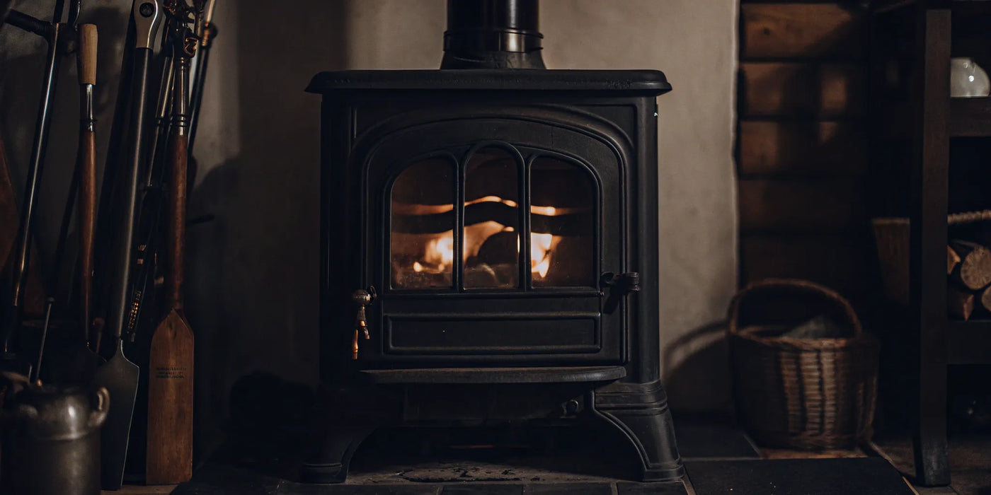 A wood stove with a fire, compatible with a universal wood stove blower kit.