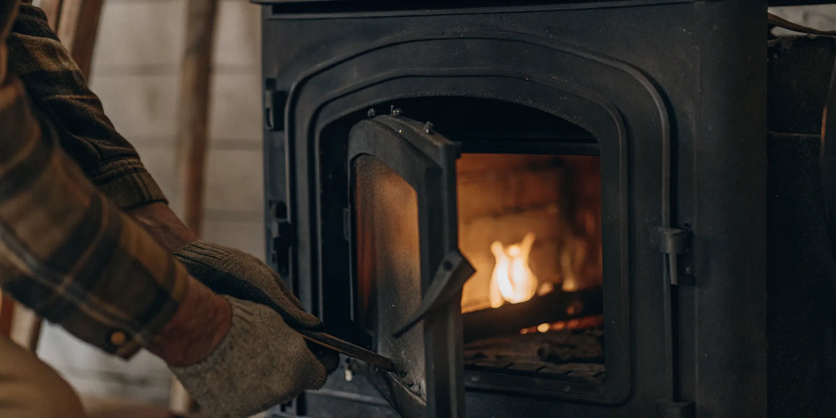 Person opening a wood stove door to inspect the gasket for replacement.