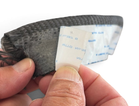 Hand peeling the adhesive backing from a Tadpole Gasket 1" x 3/8" double tadpole glass gasket.